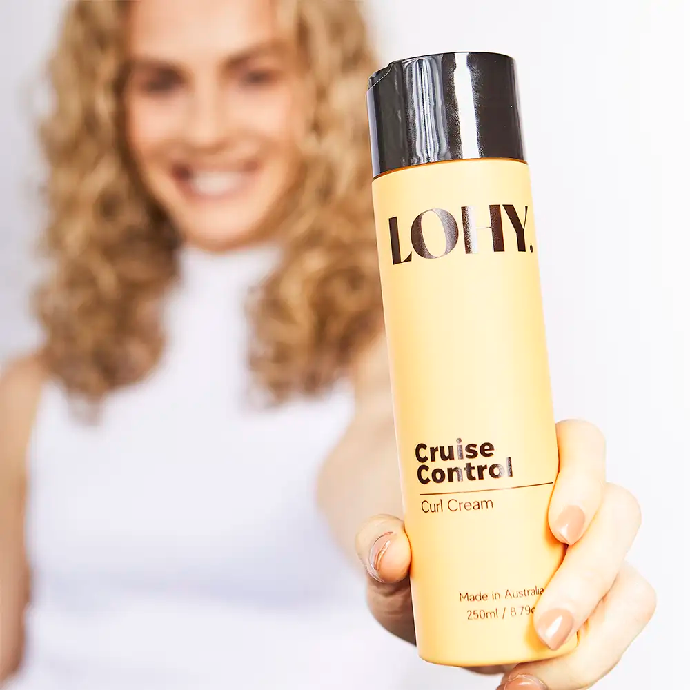 Curly girl holding a bottle of LOHY Cruise Control Curl Cream