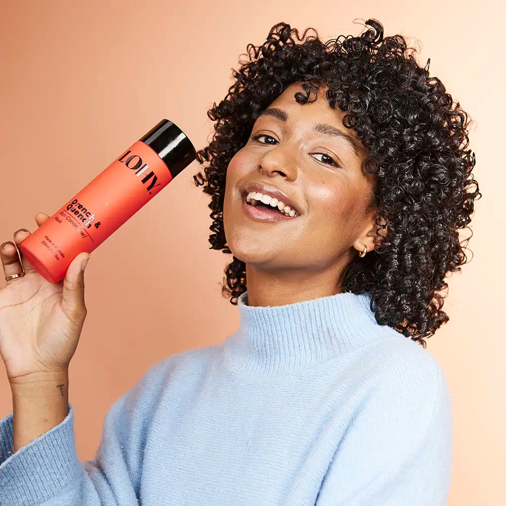 Curly girl holding a bottle of Lohy Drench &amp; Quench Rich Conditioner / Mask