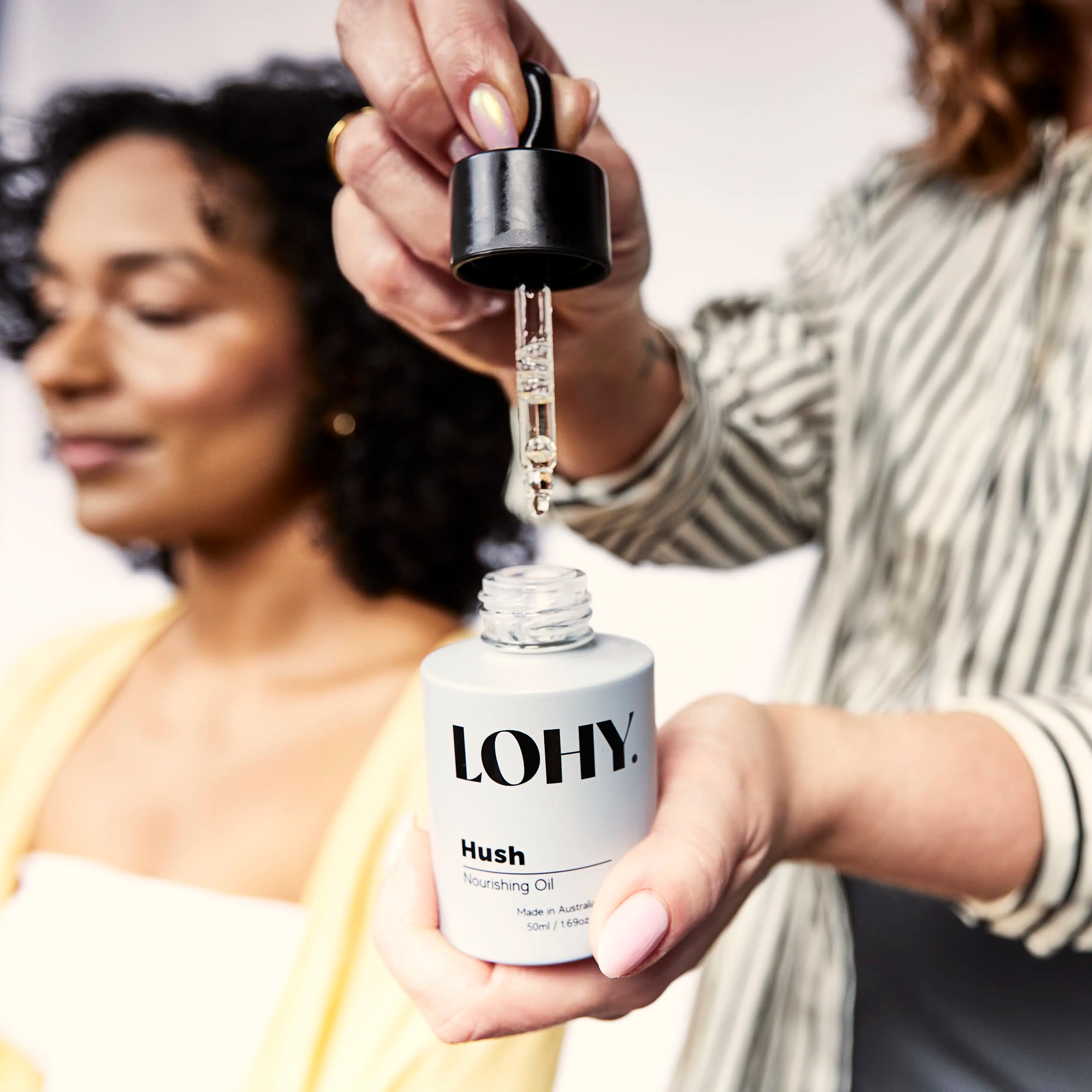 Woman pumping a few drops of LOHY Hush Nourishing Oil out of the bottle